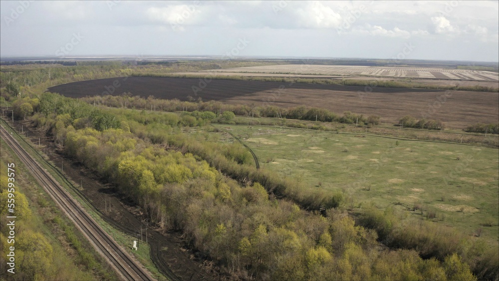 A railway track passing through the forest and field. Shooting from a height. Russian railway, taken from a height.