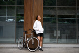 Positive african american woman posing near building and bicycle on street 