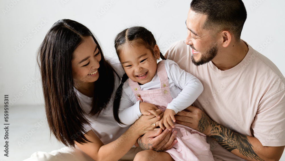 Banner of smiling young asian family playing with toddler child on grey background