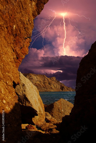 Thunderstorm over the Black Sea, Crimea. Lightning flashes over the Black Sea coast, Eastern rocky Crimea, near Feodosia and Koktebel. View through the opening in the rock