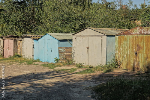 Old colored iron garages in the thickets of grass near the road in the street © butus
