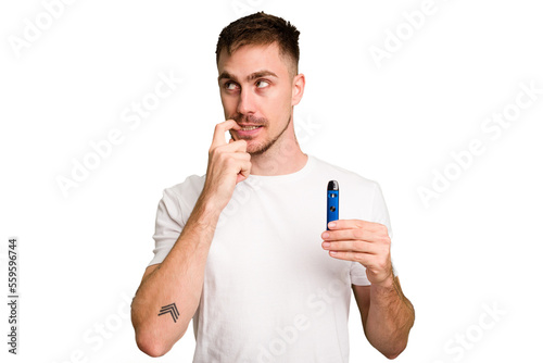 Young caucasian man holding a vaporizer cut out isolated relaxed thinking about something looking at a copy space.