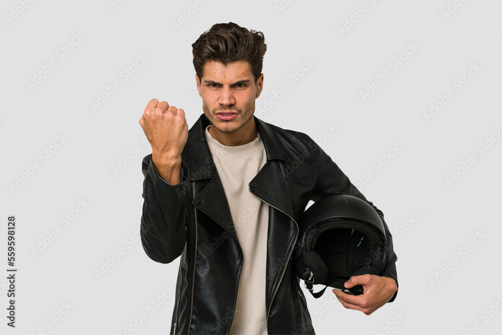 Φωτογραφία Young caucasian man holding a motrbike black helmet isolated showing fist to camera, aggressive facial expression