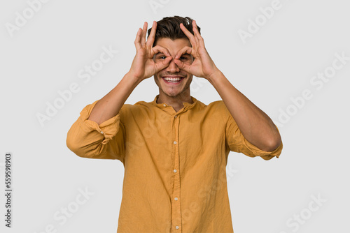 Young handsome caucasian man isolated on white background excited keeping ok gesture on eye.