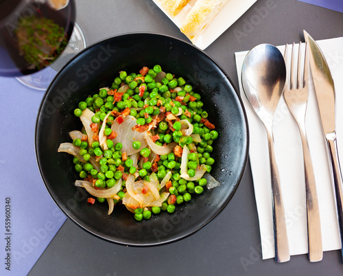Appetizing dish of green peas with ham, cooked with onions and chopped pepper