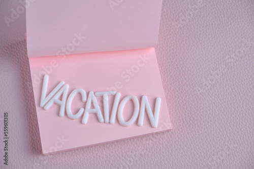 Word vacation laid out white letters pink piece paper.Concept vacation, rest and travel.