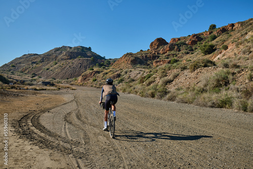 Fit male cyclist riding dirt trails on gravel bike. Man riding gravel bike on gravel road in scenic view with hills in Murcia region, Spain. Sport motivation.Gravel road in mountains. Iron ore mining 