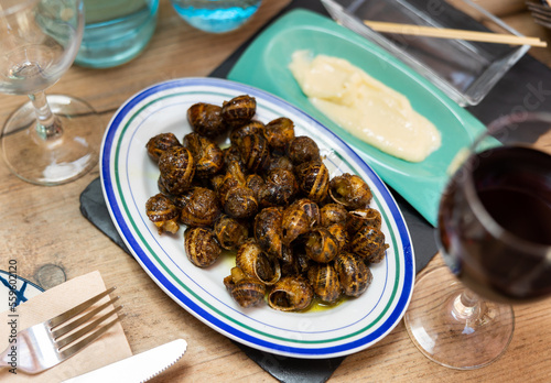 Plate of Caracoles a la llauna, delicacy of Catalan cuisine of land snails cooked in shells on grill accompanied by aioli sauce. Authentic cuisine