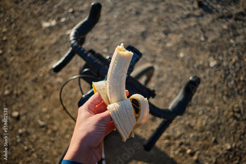 Banana on bicycle background.
Cyclist eating banana.
Healthy nutrition of a cyclist.
Healthy snack for a cyclist during training. photo