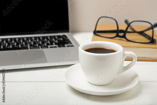 Laptop with coffee cup, eyeglasses, notepad and pen on texture background, office concept. Business concept. Work at home. Workspace with laptop. Mocap. Place for text. Copy space.