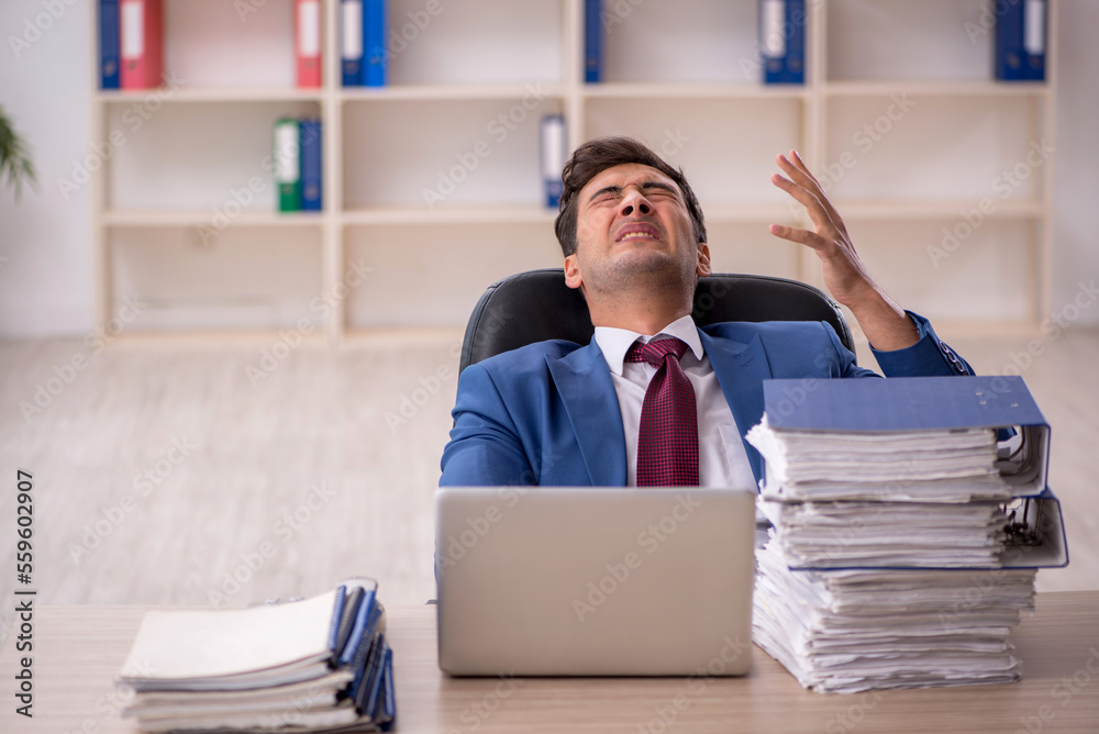 Young male employee and too much work in the office Young male employee and too much work in the office