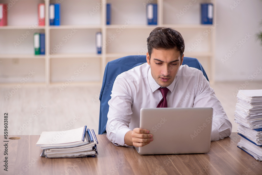 Young male employee and too much work in the office Young male employee and too much work in the office