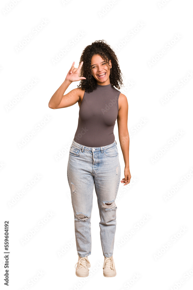 Young african american woman with curly hair cut out isolated showing a horns gesture as a revolution concept. Young african american woman with curly hair cut out isolated showing a horns gesture as a revolution concept.