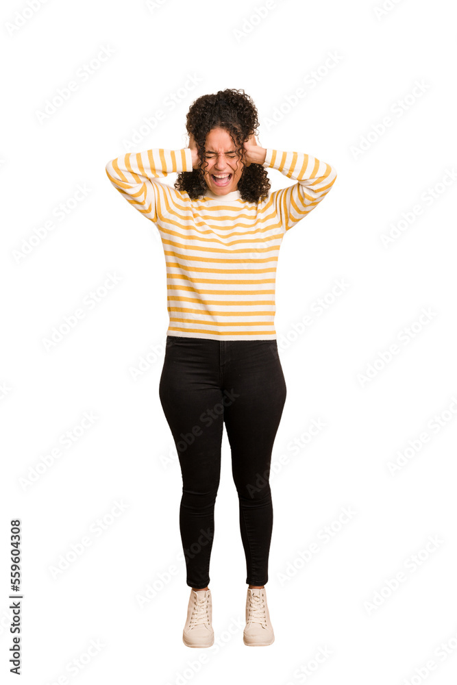 Young african american woman with curly hair cut out isolated covering ears with hands trying not to hear too loud sound. Young african american woman with curly hair cut out isolated covering ears with hands trying not to hear too loud sound.