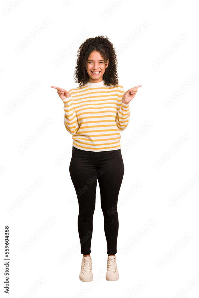 Young african american woman with curly hair cut out isolated pointing to different copy spaces, choosing one of them, showing with finger.