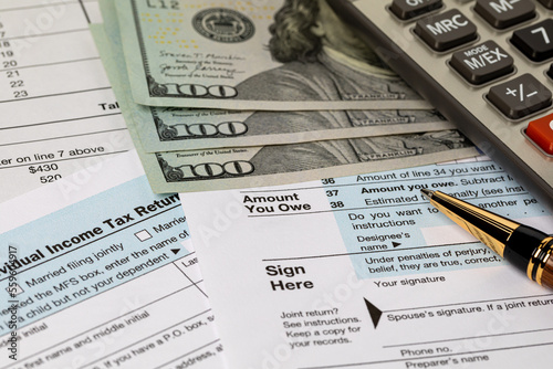 Amount you owe line on income tax return forms, cash money and calculator. Federal tax return, income tax, tax refund and payment concept.