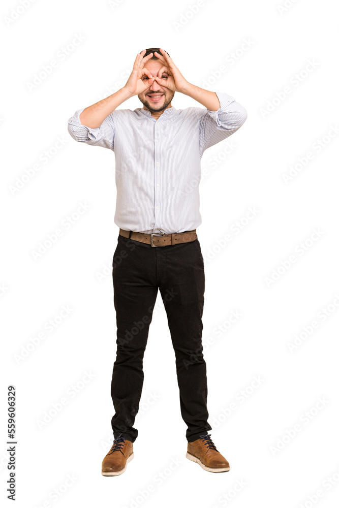 Full body adult latin man cut out isolated showing okay sign over eyes Full body adult latin man cut out isolated showing okay sign over eyes