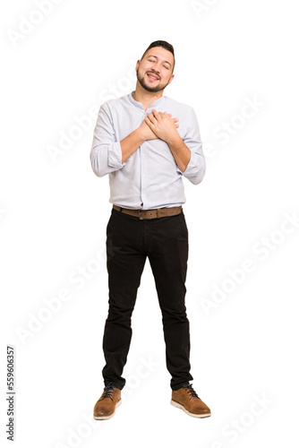 Full body adult latin man cut out isolated laughing keeping hands on heart, concept of happiness.