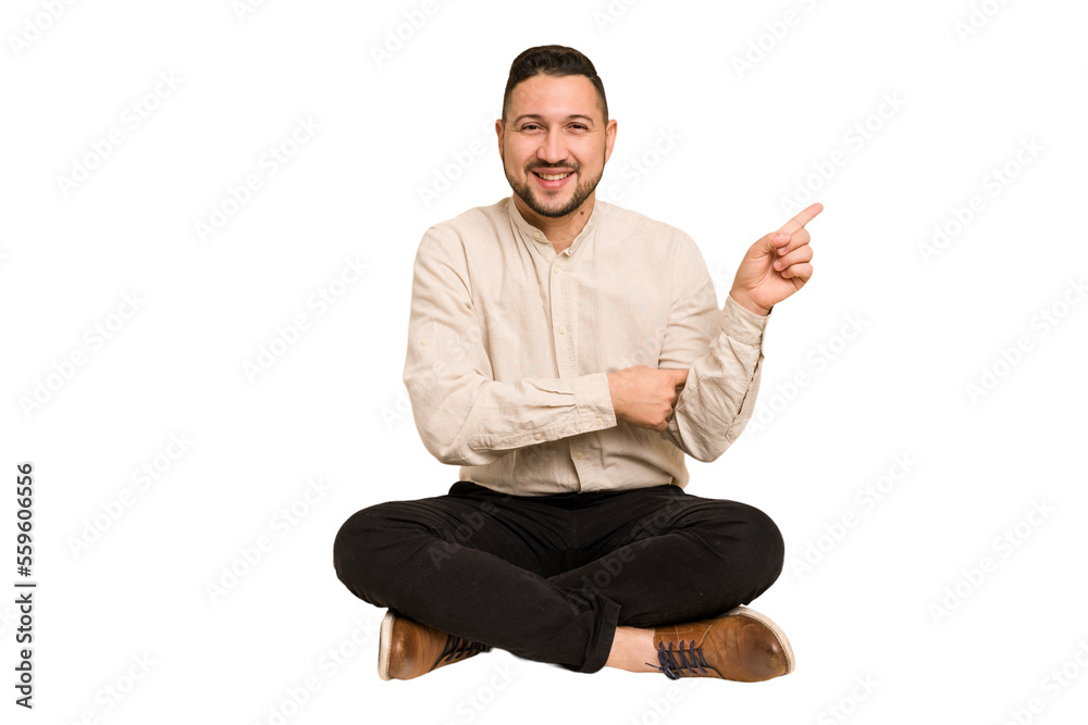 Adult latin man sitting on the floor cut out isolated smiling cheerfully pointing with forefinger away. Adult latin man sitting on the floor cut out isolated smiling cheerfully pointing with forefinger away.