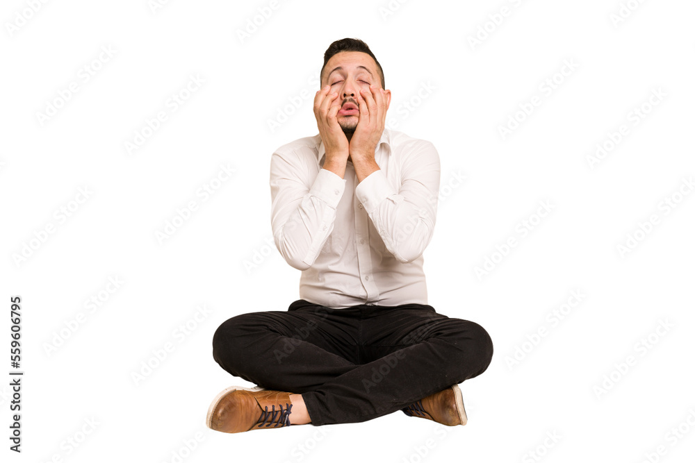 Adult latin man sitting on the floor cut out isolated whining and crying disconsolately. Adult latin man sitting on the floor cut out isolated whining and crying disconsolately.