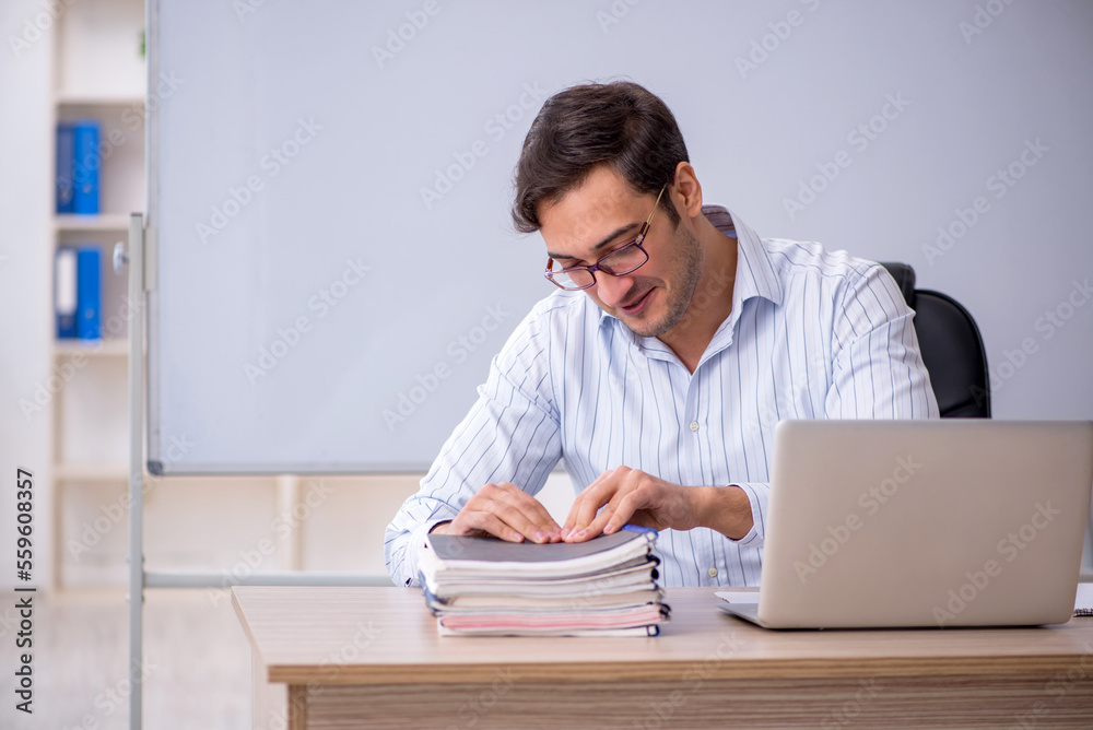 Young male teacher sitting in the classroom