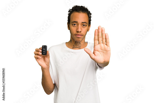 Young African American man holding car keys isolated standing with outstretched hand showing stop sign, preventing you.