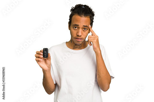 Young African American man holding car keys isolated pointing temple with finger, thinking, focused on a task.