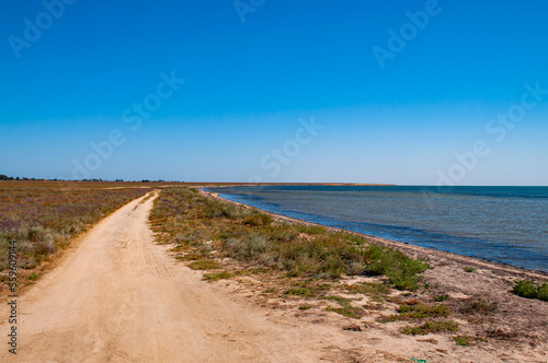 Dirt road along the salt lake against a clear blue sky