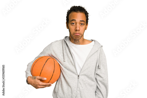 Young african american man playing basketball isolated shrugs shoulders and open eyes confused.