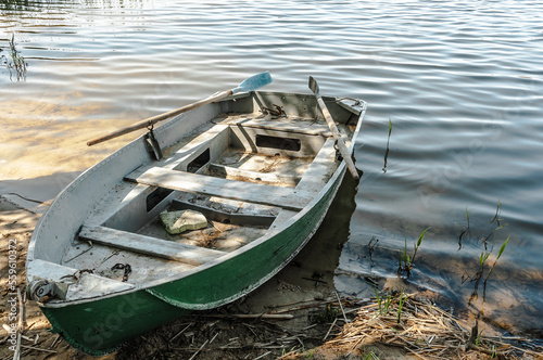 Old boat with oars on the shore of the forest lake.