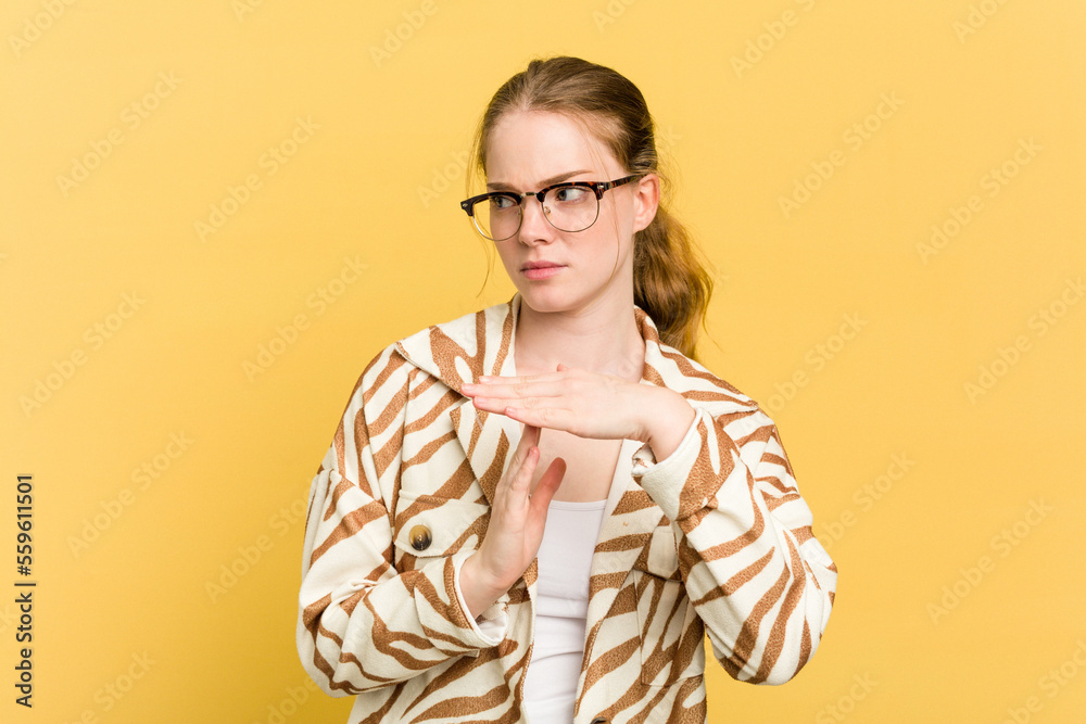 Young caucasian redhead woman isolated on yellow background showing a timeout gesture.