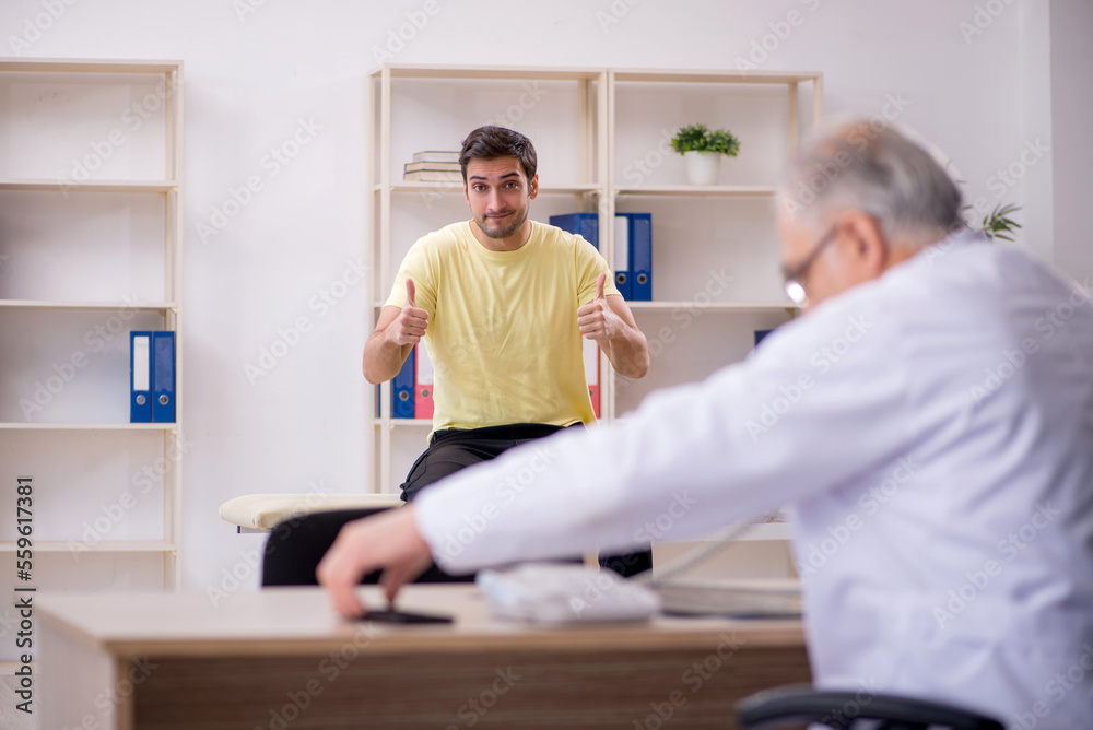 Fototapeta premium Young male patient visiting old male doctor