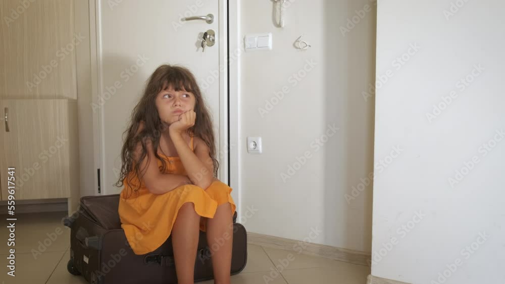 Child on luggage at first trip abroad. A view of little girl sits on luggage before her first summer trip. Child on luggage at first trip abroad. A view of little girl sits on luggage before her first summer trip.