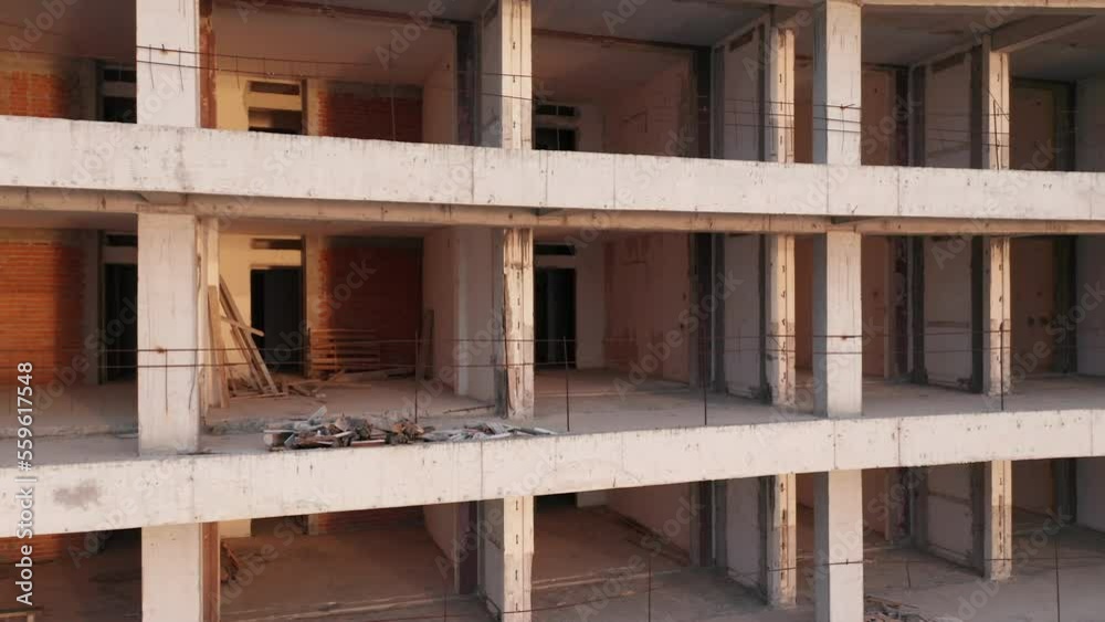 Building under construction - reinforced concrete high-rise multistory tower block renovation. Geometric grid-like pattern of walls and slabs in a housing project. Civil engineering and architecture. Building under construction - reinforced concrete high-rise multistory tower block renovation. Geometric grid-like pattern of walls and slabs in a housing project. Civil engineering and architecture.