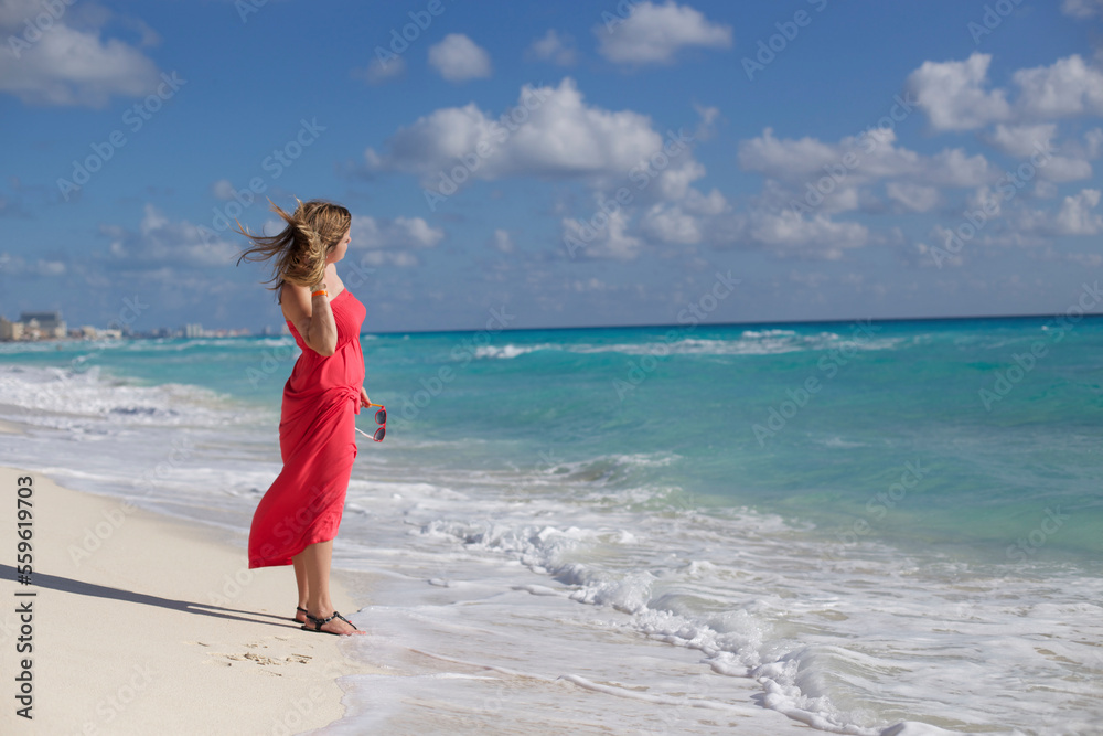 Woman in red dress standing on beach, Cancun, Quintana Roo, Mexico Woman in red dress standing on beach, Cancun, Quintana Roo, Mexico