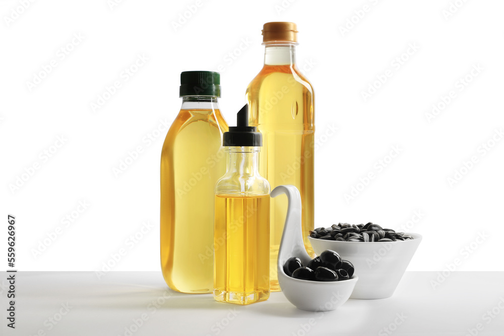 Bottles of different cooking oils, olives and sunflower seeds on white background Bottles of different cooking oils, olives and sunflower seeds on white background