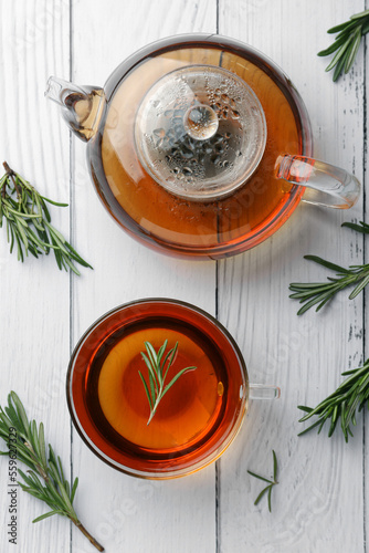Aromatic herbal tea with rosemary on white wooden table, flat lay