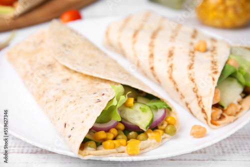 Delicious hummus wraps with vegetables on table, closeup
