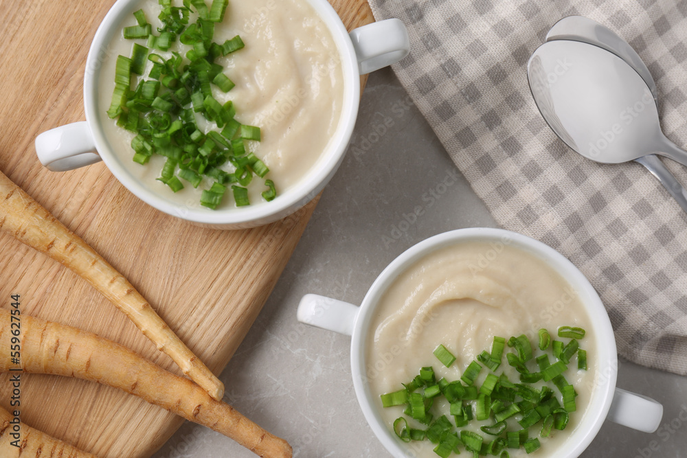 Bowls with tasty creamy soup of parsnip served on light grey table, flat lay Bowls with tasty creamy soup of parsnip served on light grey table, flat lay