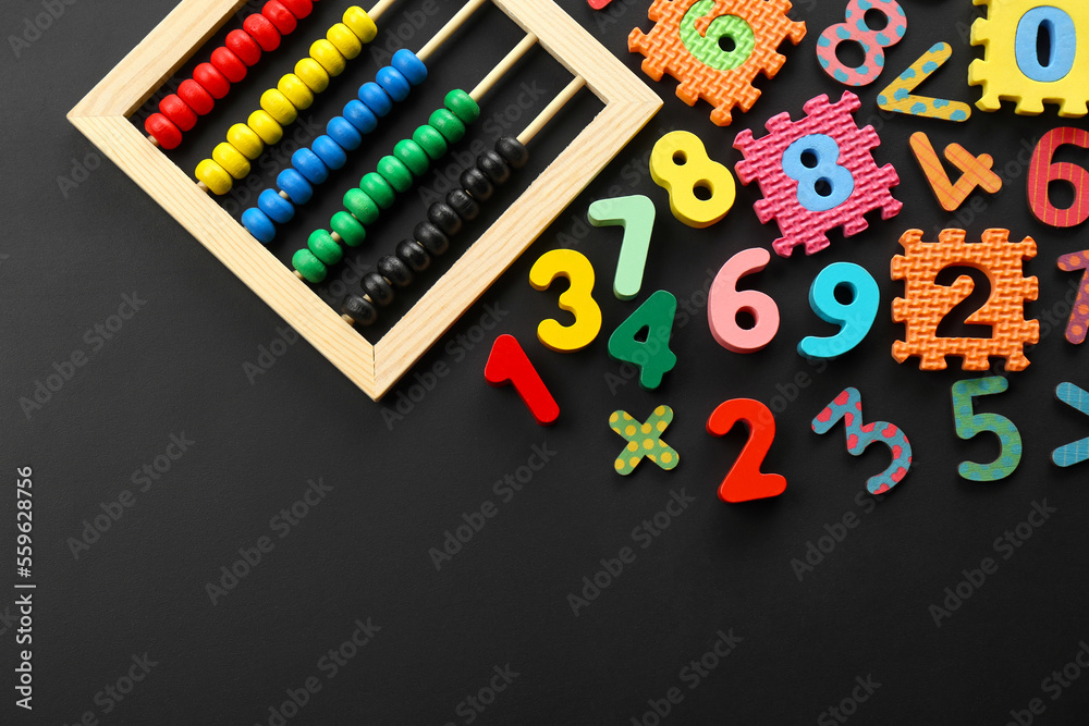 Fototapeta premium Many colorful numbers and mathematical symbols near abacus on black background, flat lay. Space for text