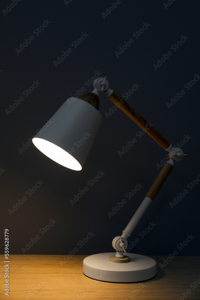 Stylish modern desk lamp on wooden table at night Stylish modern desk lamp on wooden table at night
