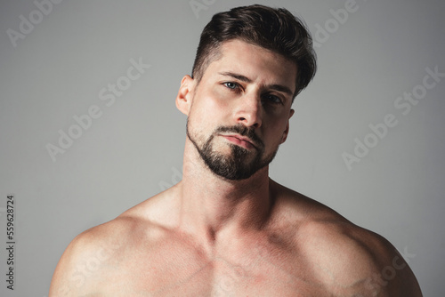 Portrait of a handsome young man with stylish haircut posing over gray background. Perfect body&skin. Studio shot.
