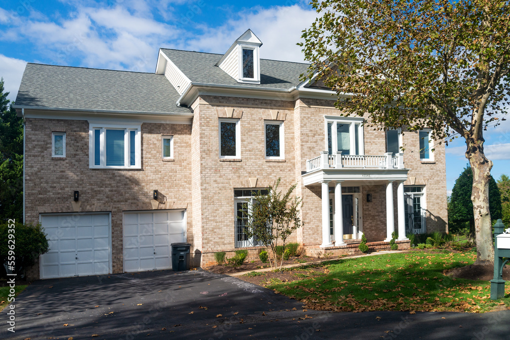 Two-story brick house with a garage and a green lawn Two-story brick house with a garage and a green lawn
