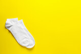 Pair of white socks on yellow background, flat lay. Space for text