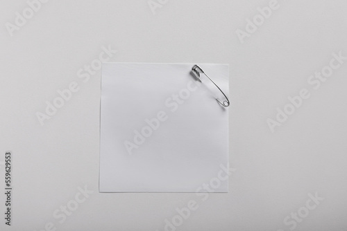 Paper note attached with safety pin on white background, top view