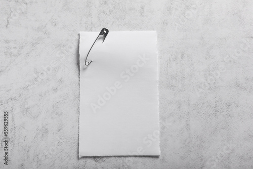 Sheet of paper attached with safety pin on grey textured background, top view