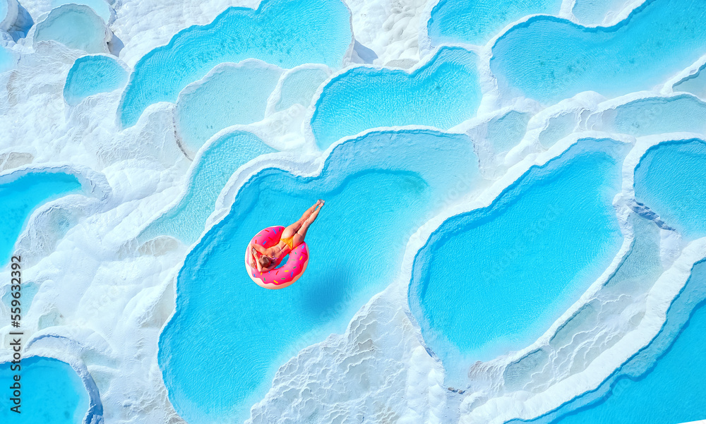 Travertine pools Pamukkale, Turkey travel. Woman swimming on pink inflatable donut in turquoise water, aerial top view - obrazy, fototapety, plakaty 