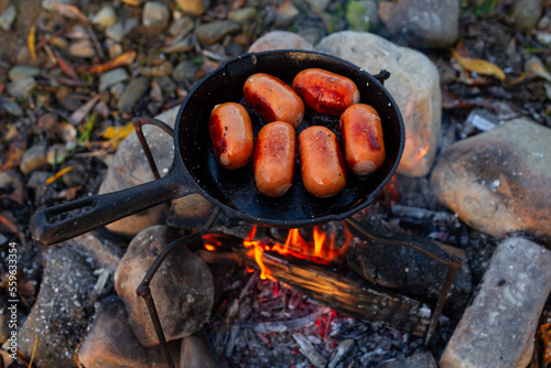 Sausage on the pan over an open fire. Preparing food in nature.