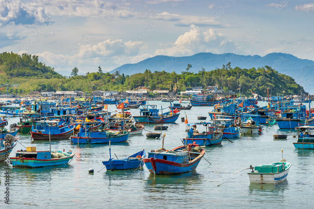 A small bay with many brightly painted fishing boats and mountains behind at Vihn Luong in Vietnam