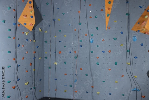 Climbing wall with holds and ropes in gym. Extreme sport